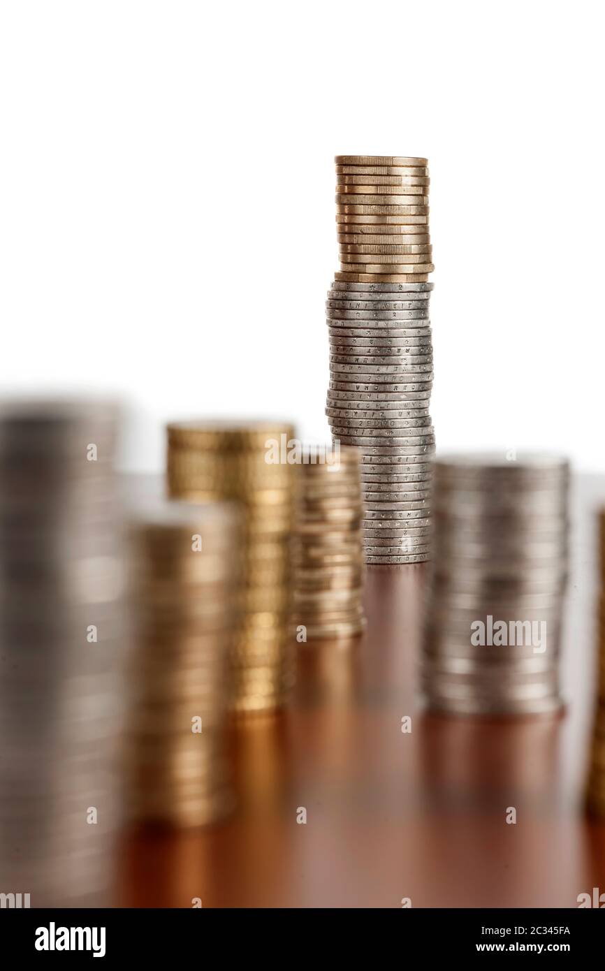 Flat-angled view of stacked euro coins on smooth wooden surface and focus on the rear stack with aperture F11. Stock Photo