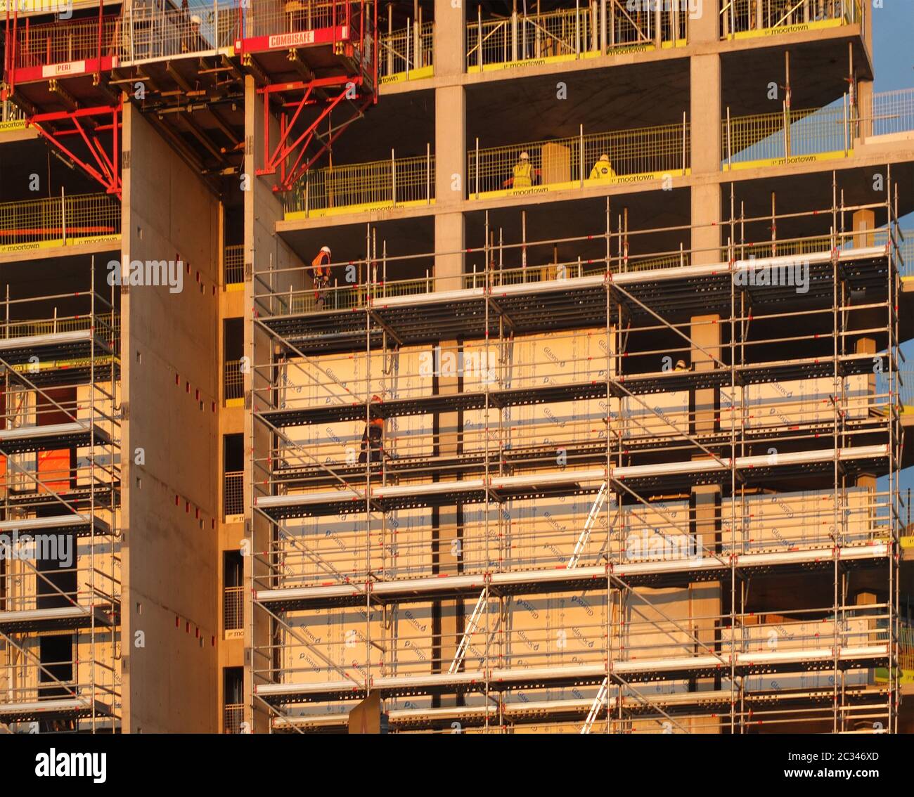 builders working on scaffolding and platforms on different floors of a large modern construction site Stock Photo