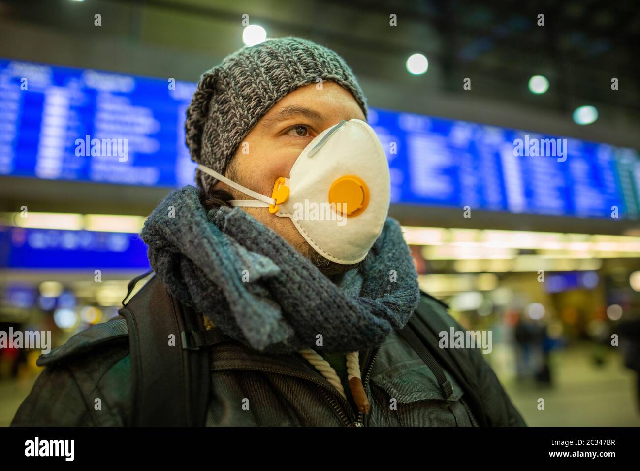Man wearing a respirator mask device for health protection at an airport or railway train station in Stock Photo