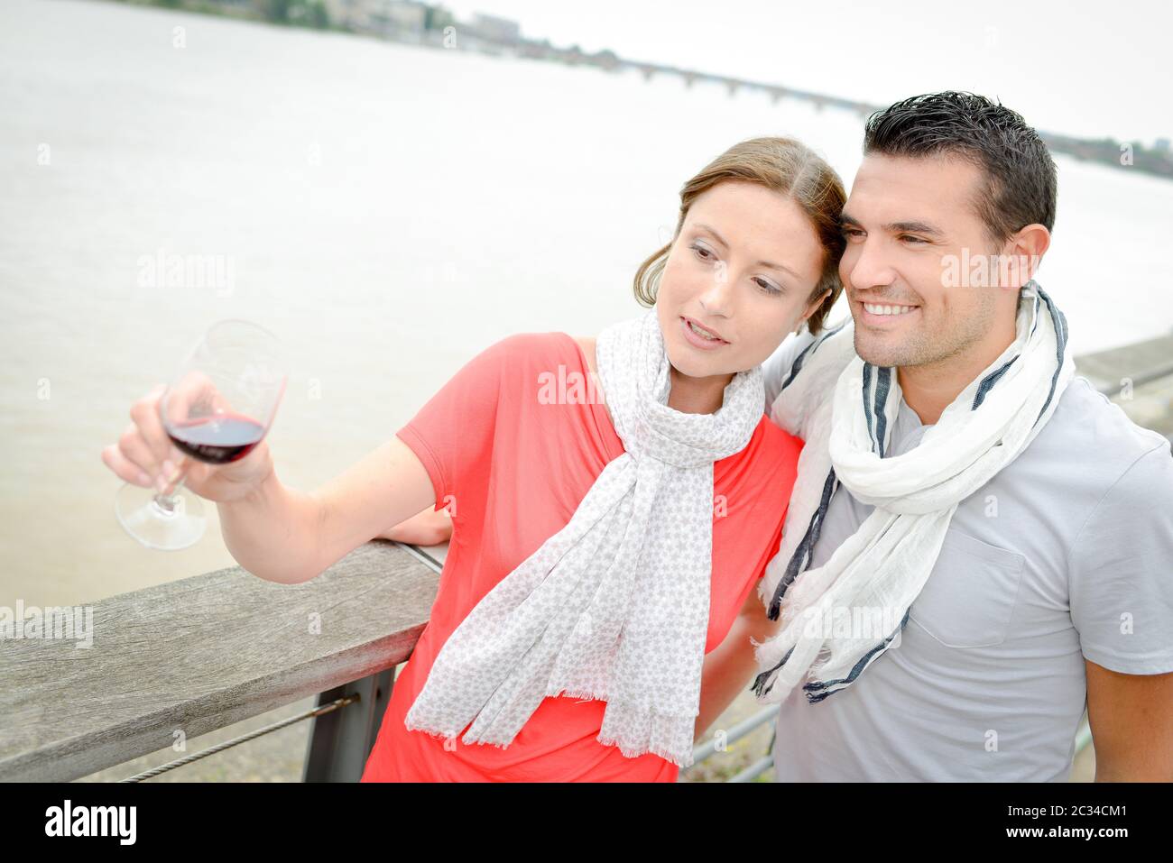 Couple by river, lady holding glass of red wine Stock Photo - Alamy