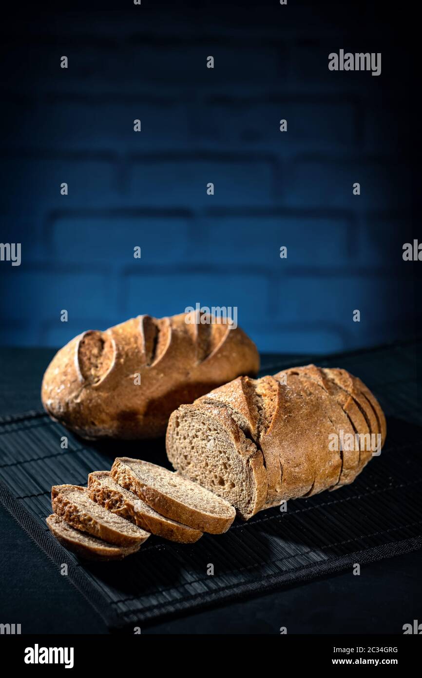 Gluten free multi dark bread on a black table and blue bricks background Stock Photo
