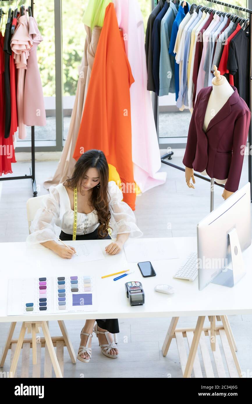Top view a young adult fashion designer drawing and sketching her work ...