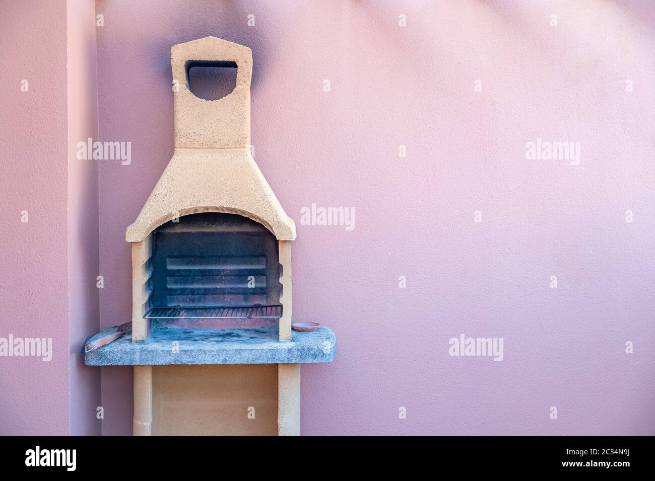 Traditional stone grill with pink wall in the background. Copy space. Stock Photo
