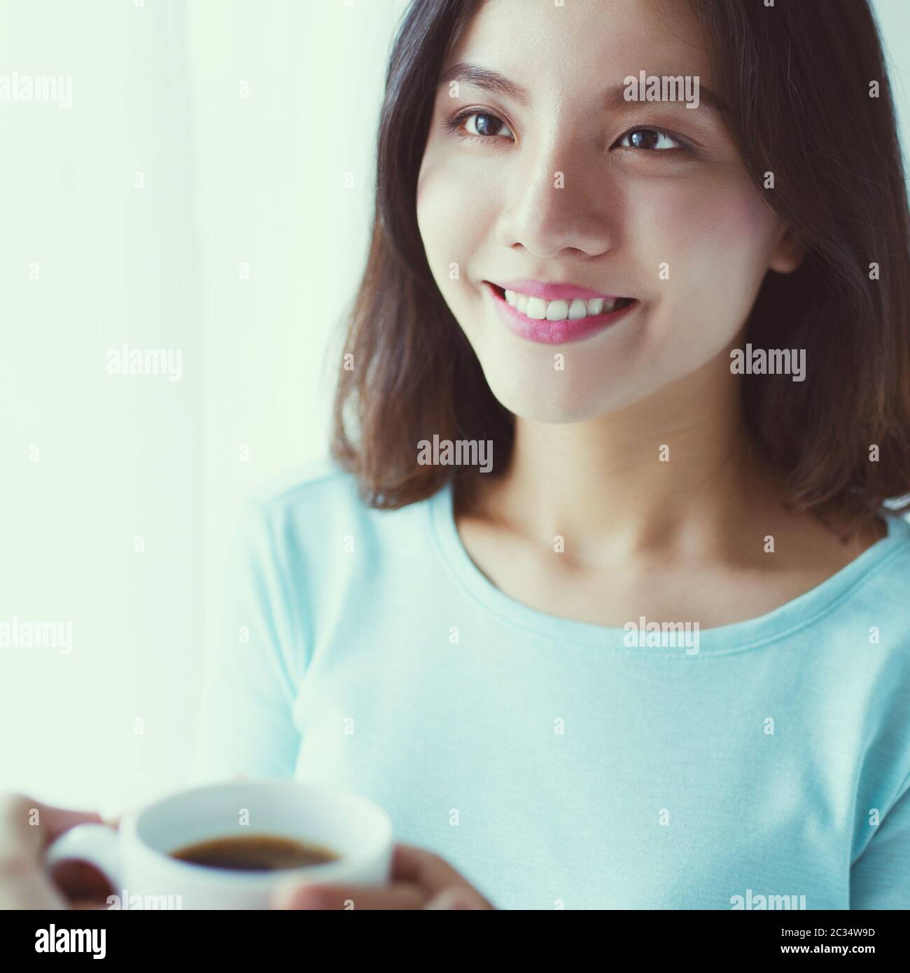 Portrait of young Asian woman drinking coffee behind the window Stock