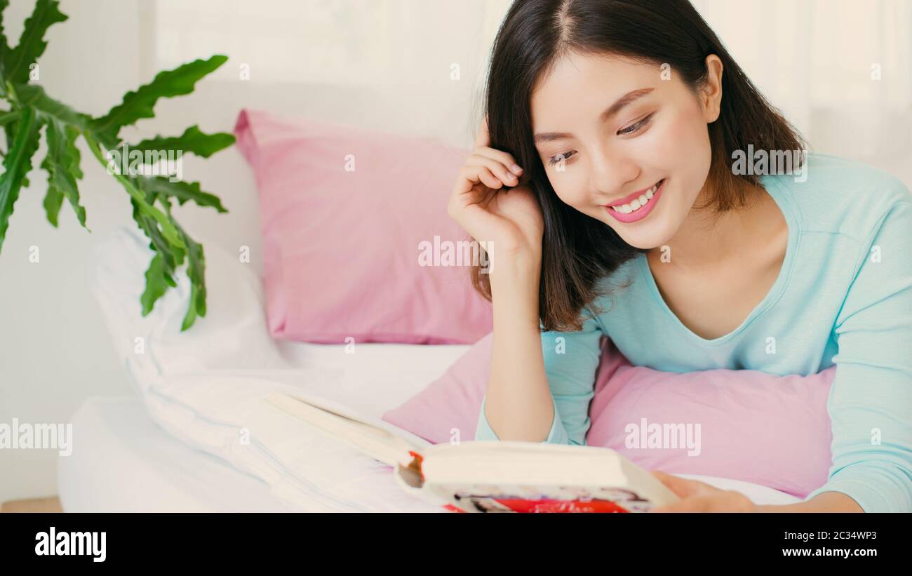 Young woman reading book in bed in the weekend. Stock Photo