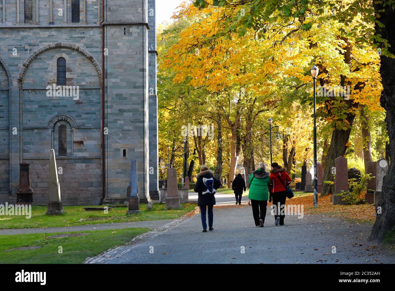 Trondheim, Norway - October 14, 2019: People walking the churchyard outside the Nidaros cathedral with trees in autumn colors. Stock Photo