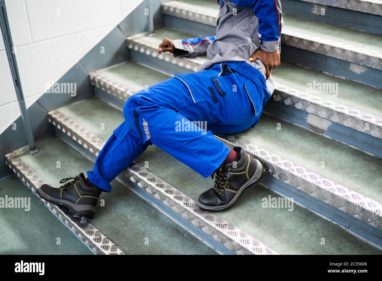 Worker Man Lying On Staircase After Slip And Fall Accident Stock Photo