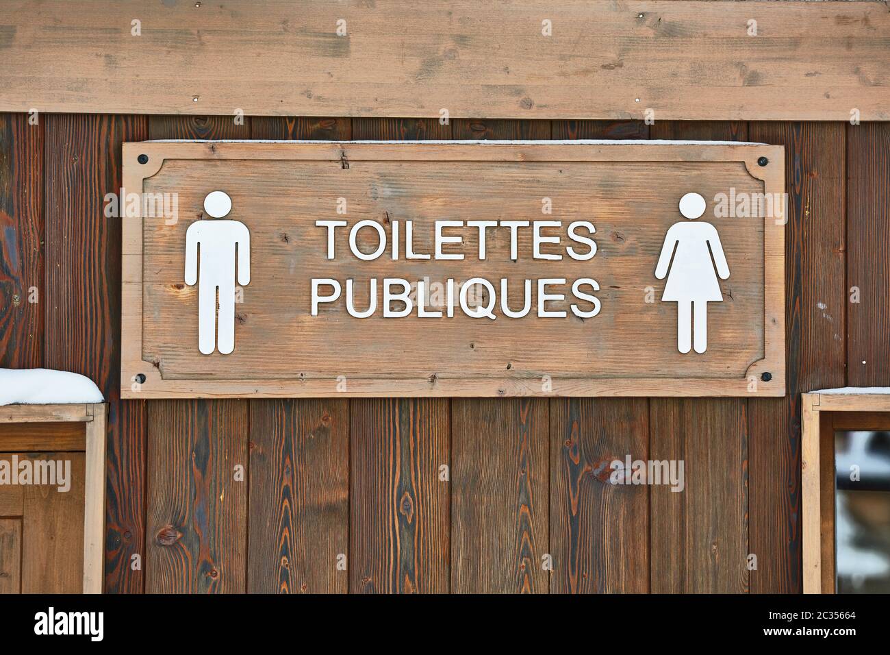 Public toilets signs on a wooden building in France. Sign in French reads Public Toilets
