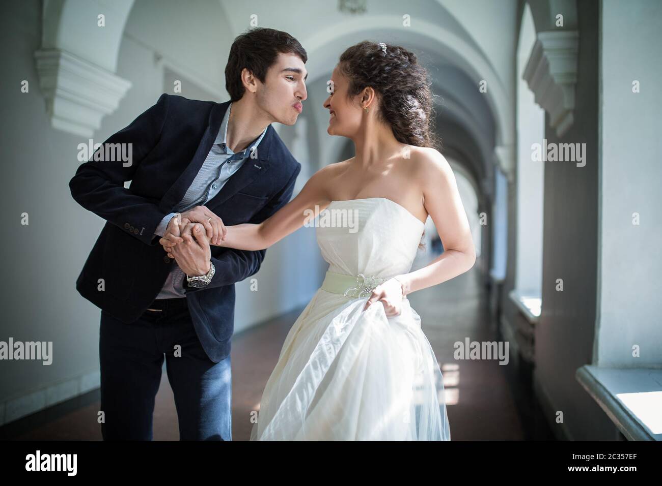 Happy couple playfully goes down a long corridor Stock Photo