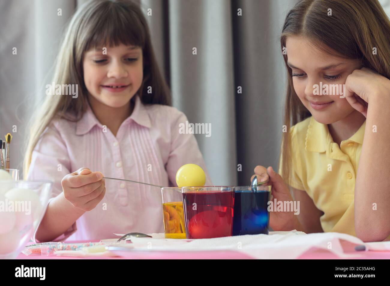 Children paint Easter eggs in glasses with liquid dye Stock Photo