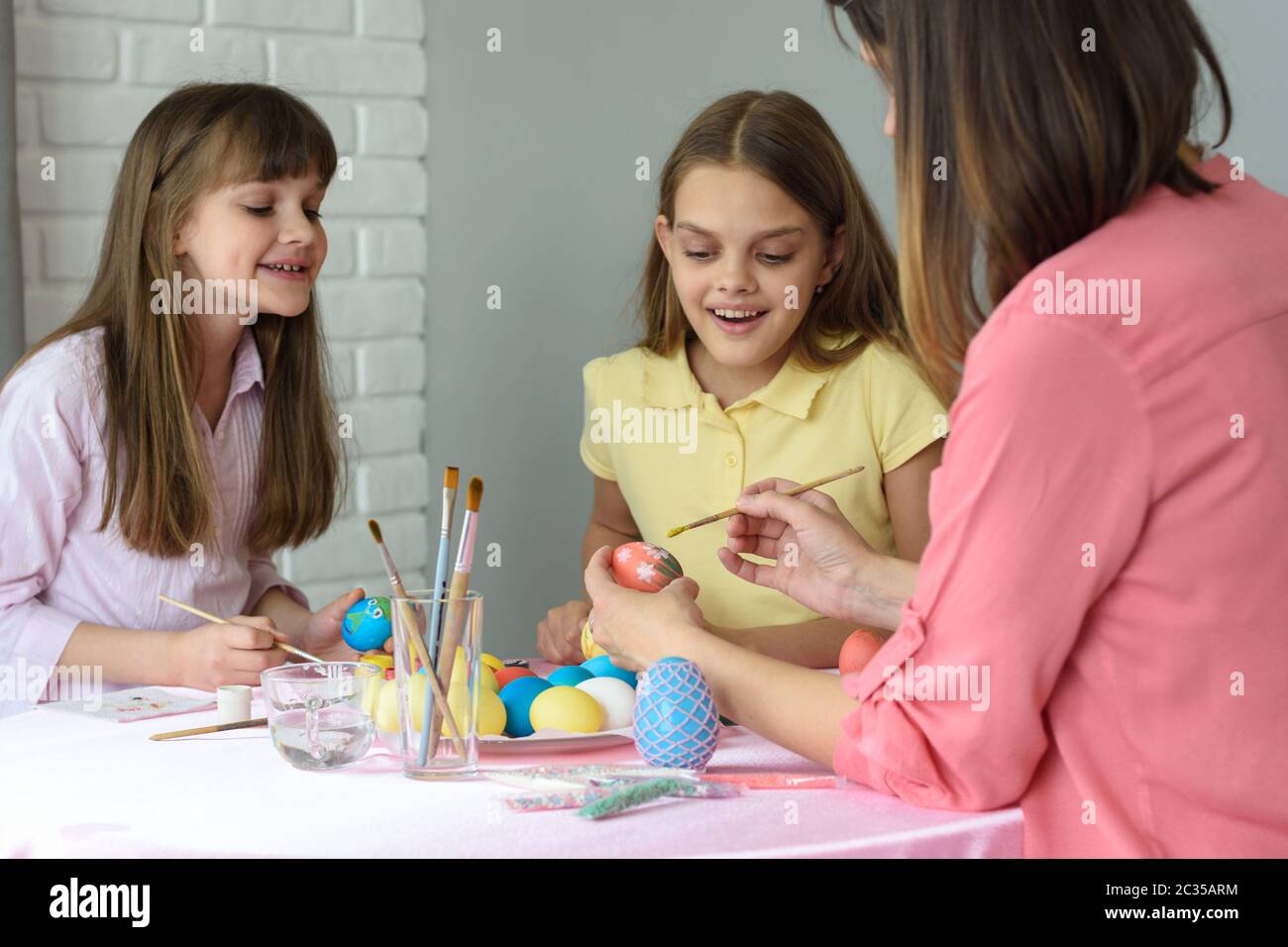 Mom with two daughters paint eggs for Easter Stock Photo