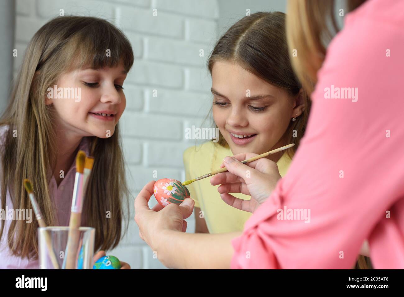 Children watch mom paint Easter eggs beautifully Stock Photo