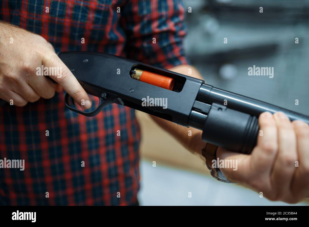 Male person loads rifle at showcase in gun shop. Euqipment for hunters ...