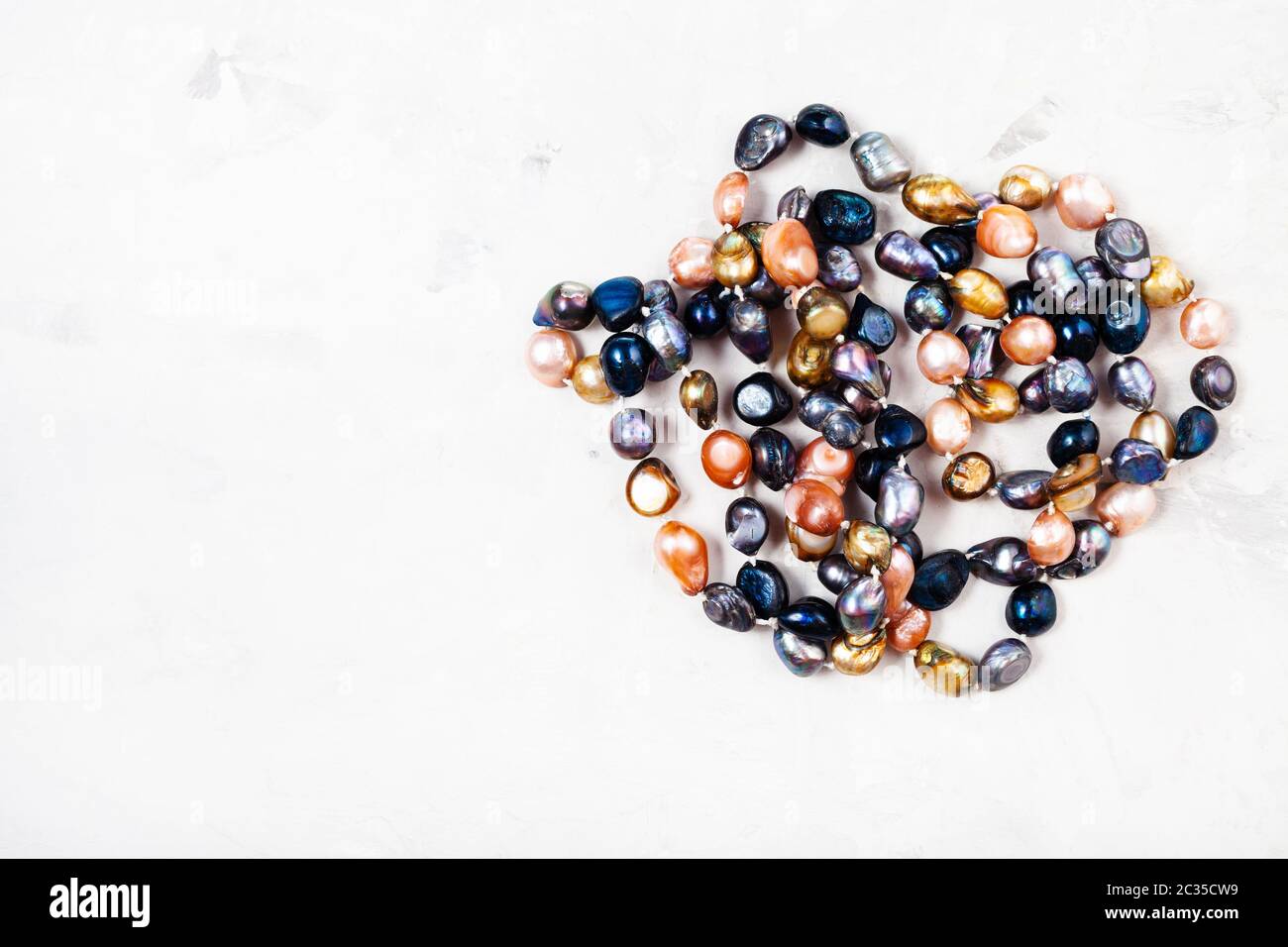 tangled hand crafted necklace from various river pearls on gray concrete background with copyspace Stock Photo