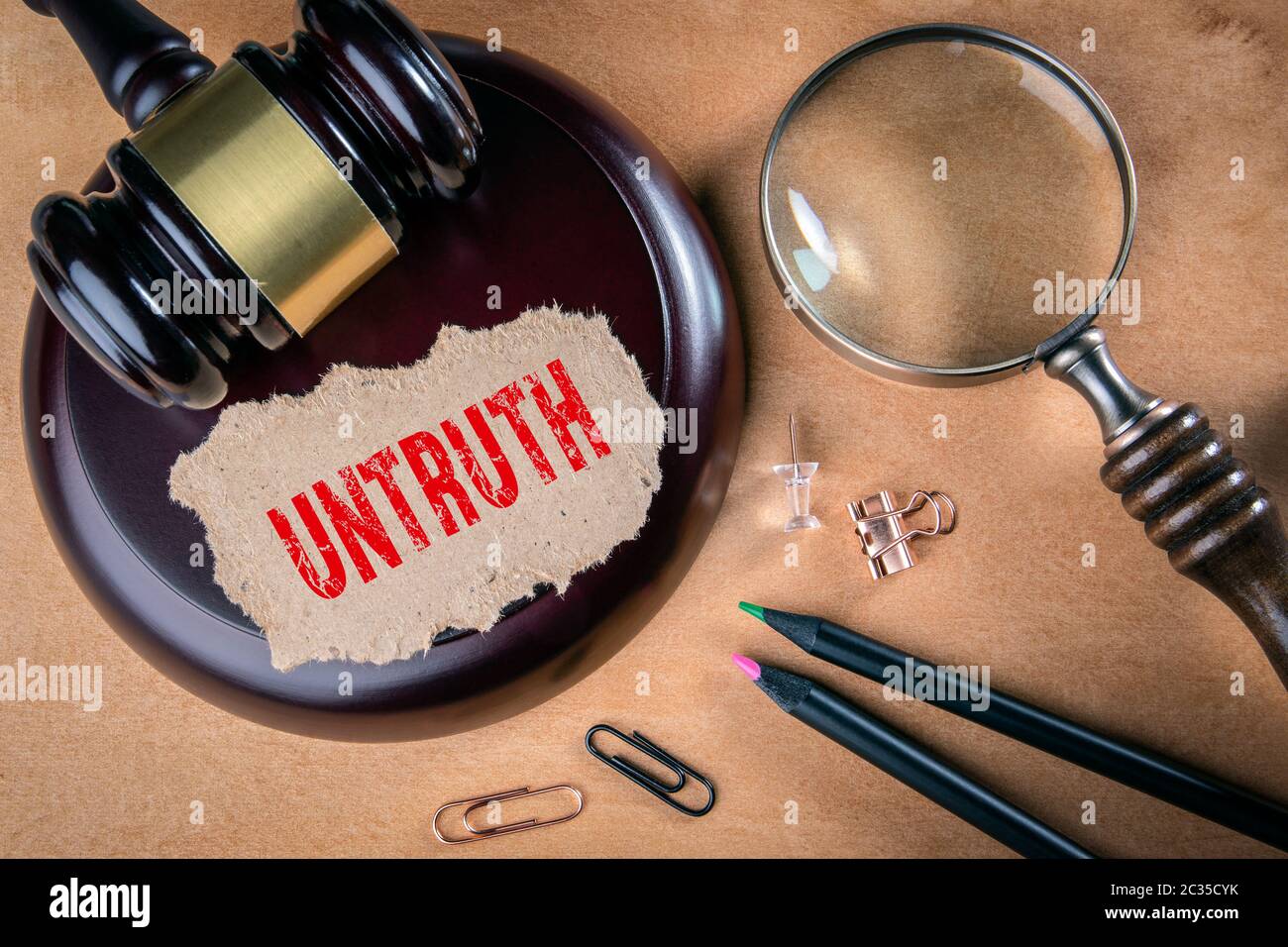 UNTRUTH. Law, regulations and judgment concept. Judge's hammer, stationery and magnifying glass on the table Stock Photo