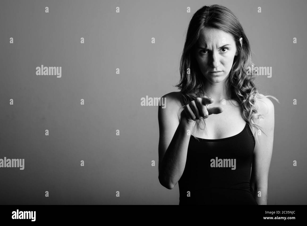 Young beautiful woman wearing sleeveless top against gray background Stock Photo