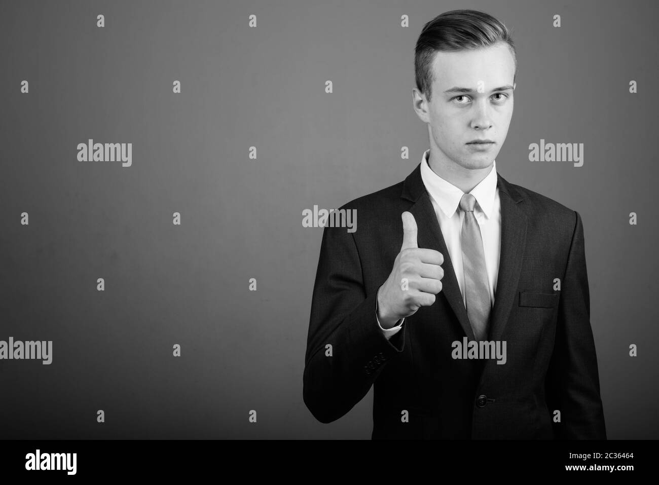 Young handsome businessman wearing suit against gray background Stock ...
