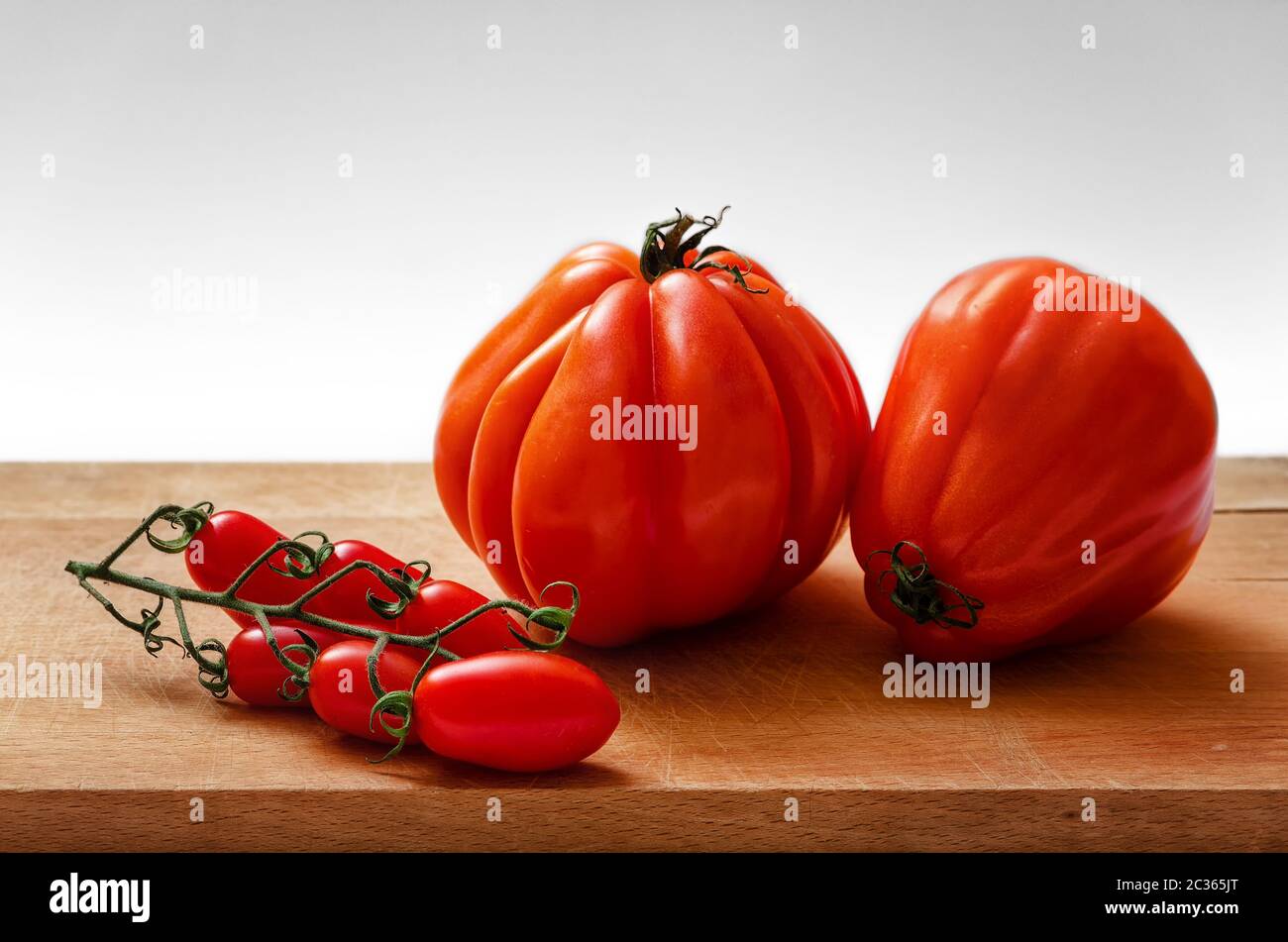 Tomatoes on a chopping board with white background Stock Photo - Alamy