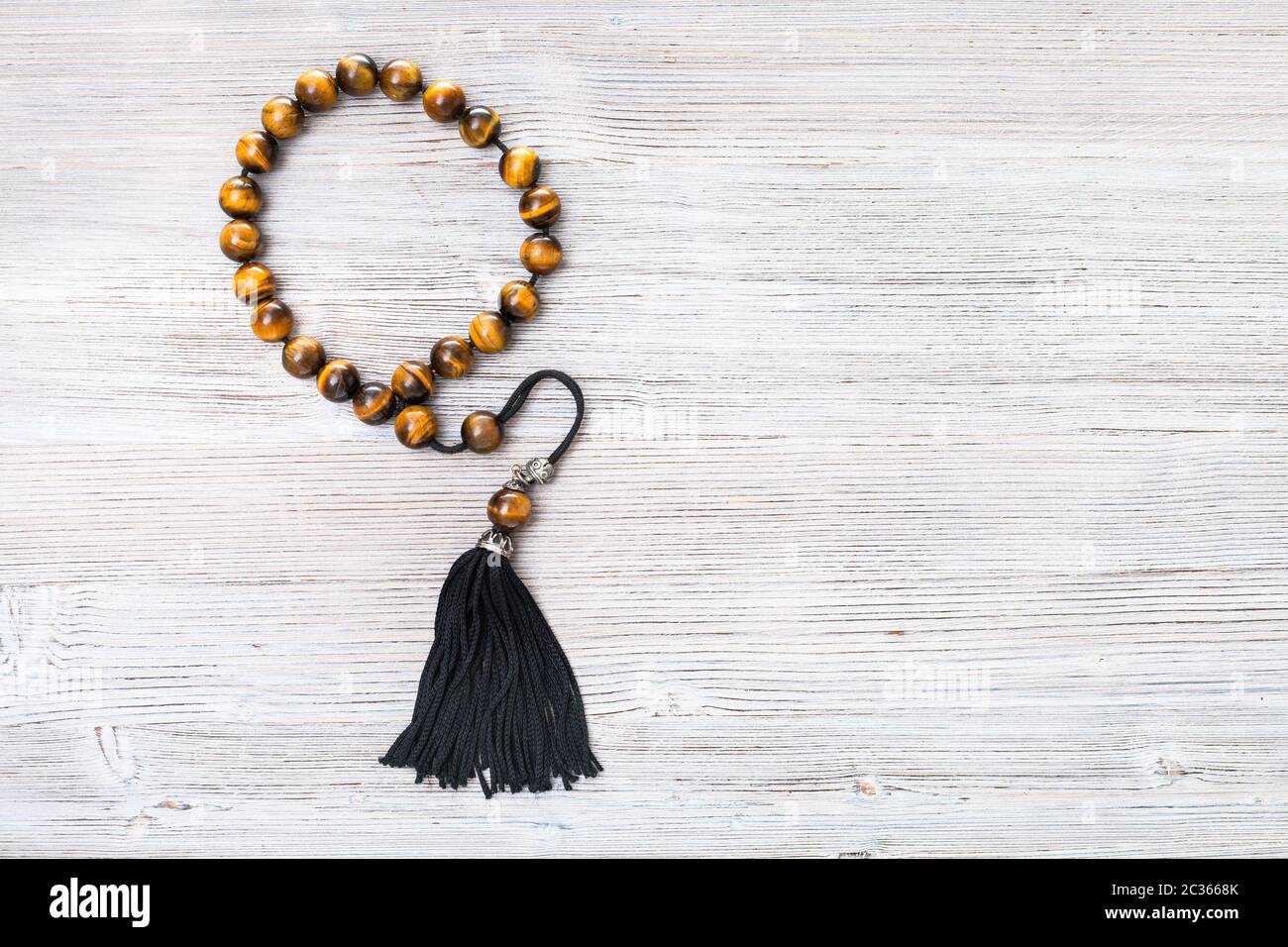 top view of tiger's eye worry beads on gray wooden board with copyspace Stock Photo