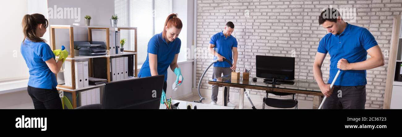 Group Of Janitors Cleaning The Office With Caution Wet Floor Sign Stock Photo