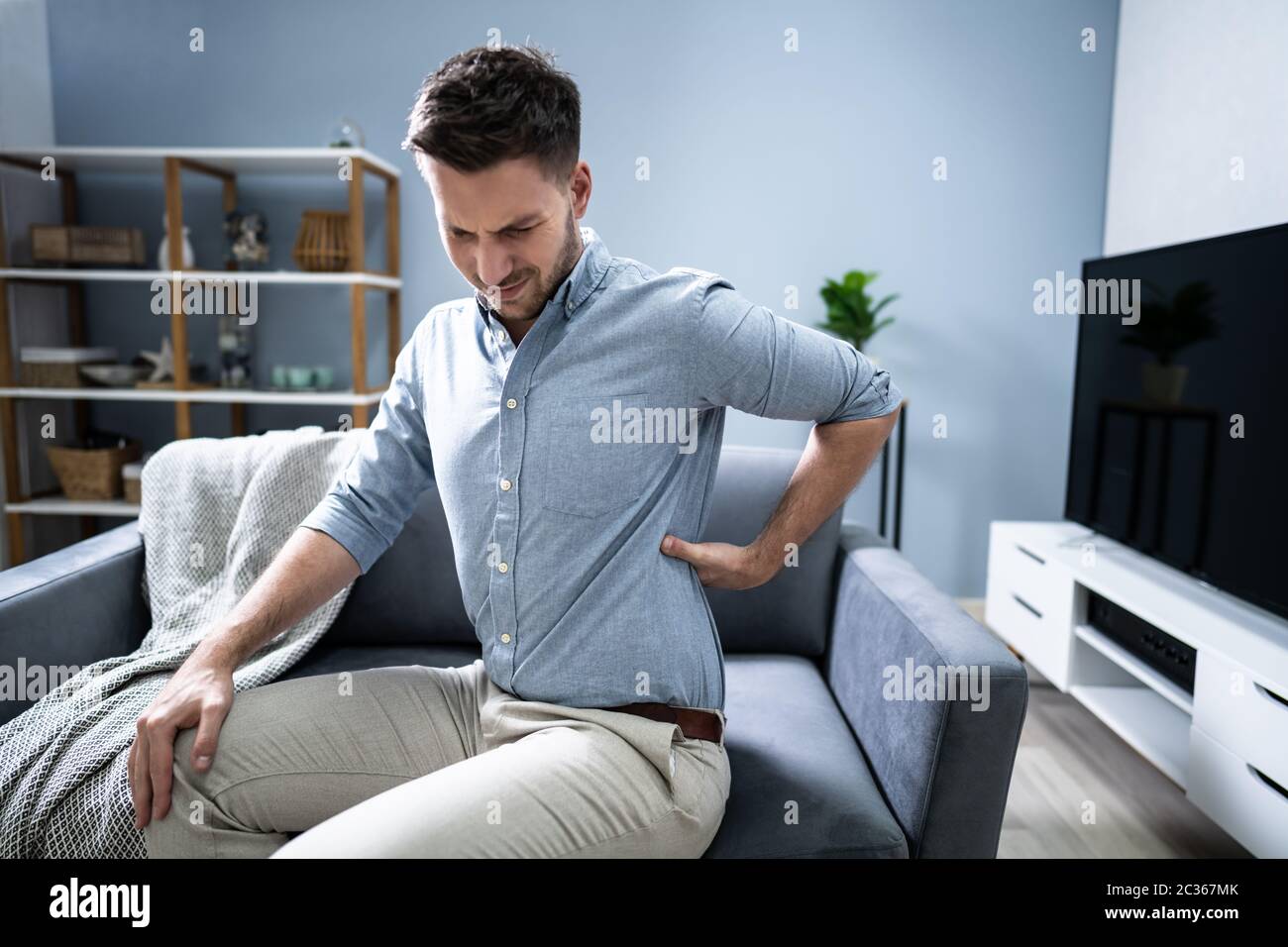 Mature Man Having Backache While Sitting On Sofa Stock Photo - Alamy
