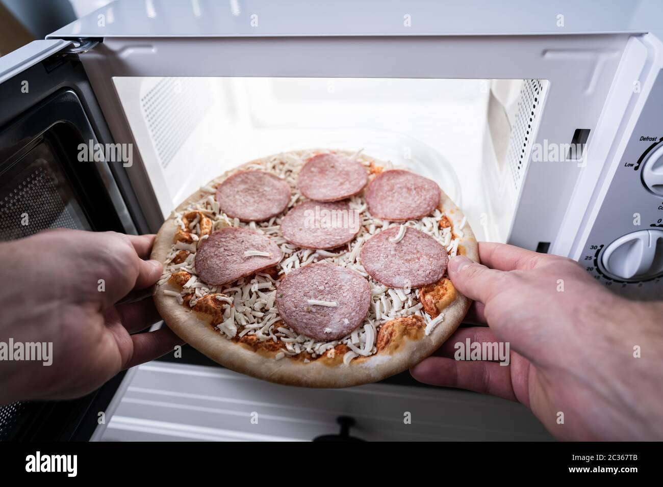 Human Hand Baking Pizza In Microwave Oven Stock Photo Alamy