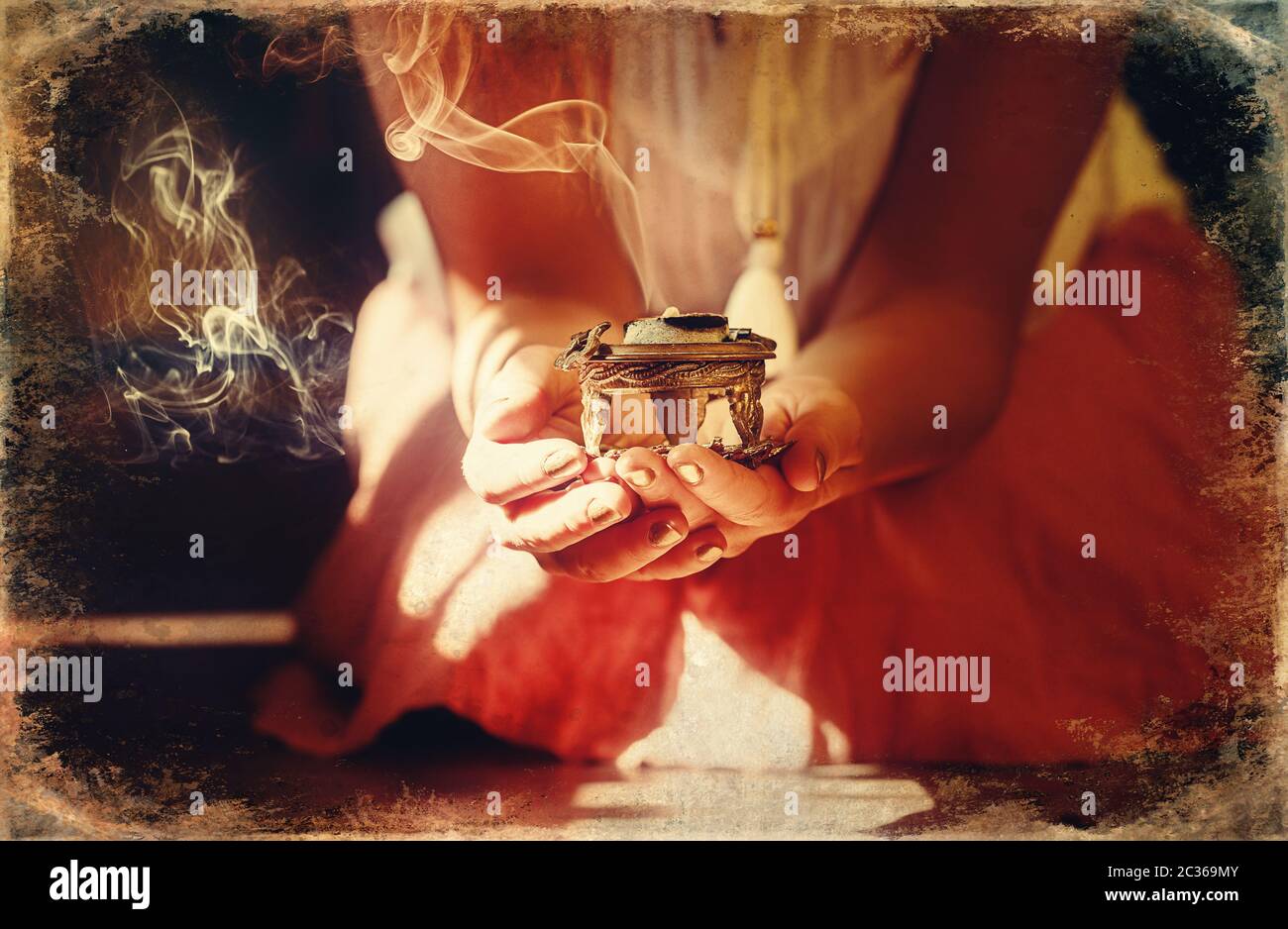 incense in a woman hand, incense smoke on a black background. Old photo