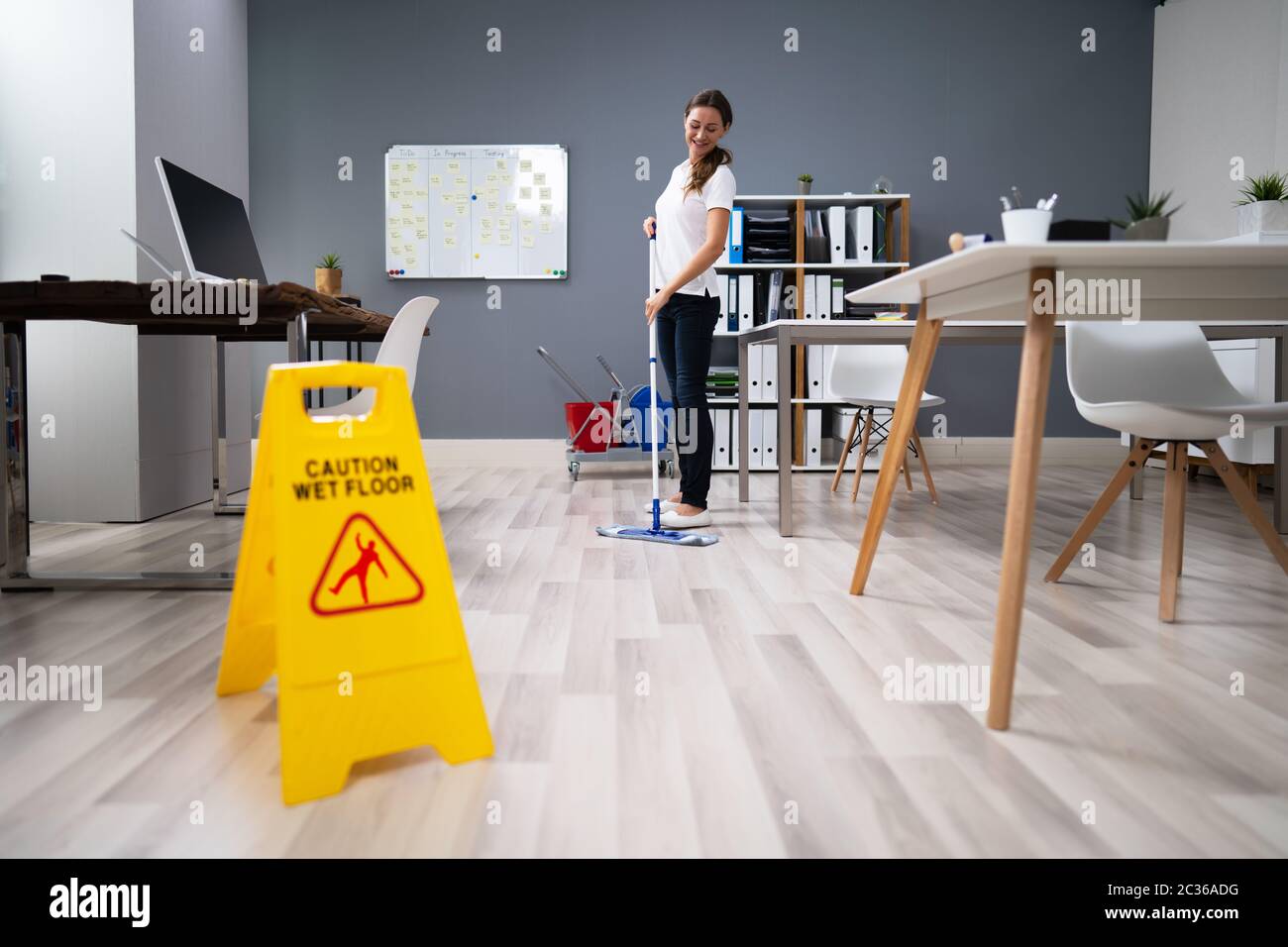 Full Length Of Female Janitor Mopping Floor In Office Stock Photo