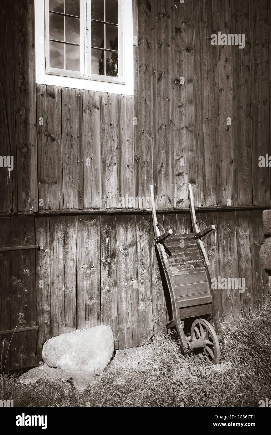 Old wooden wheelbarrow on a farm wall. Black and White photography Stock Photo