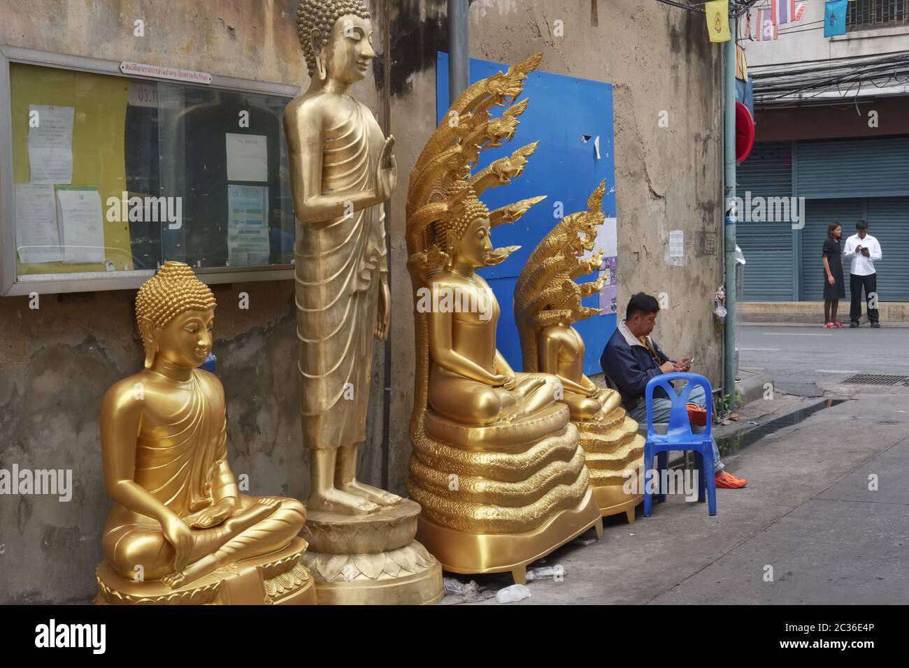 Buddha statues stand in front of a factory for Buddha statues and other religious objects in a side lane off Bamrung Muang Road, Bangkok, Thailand Stock Photo