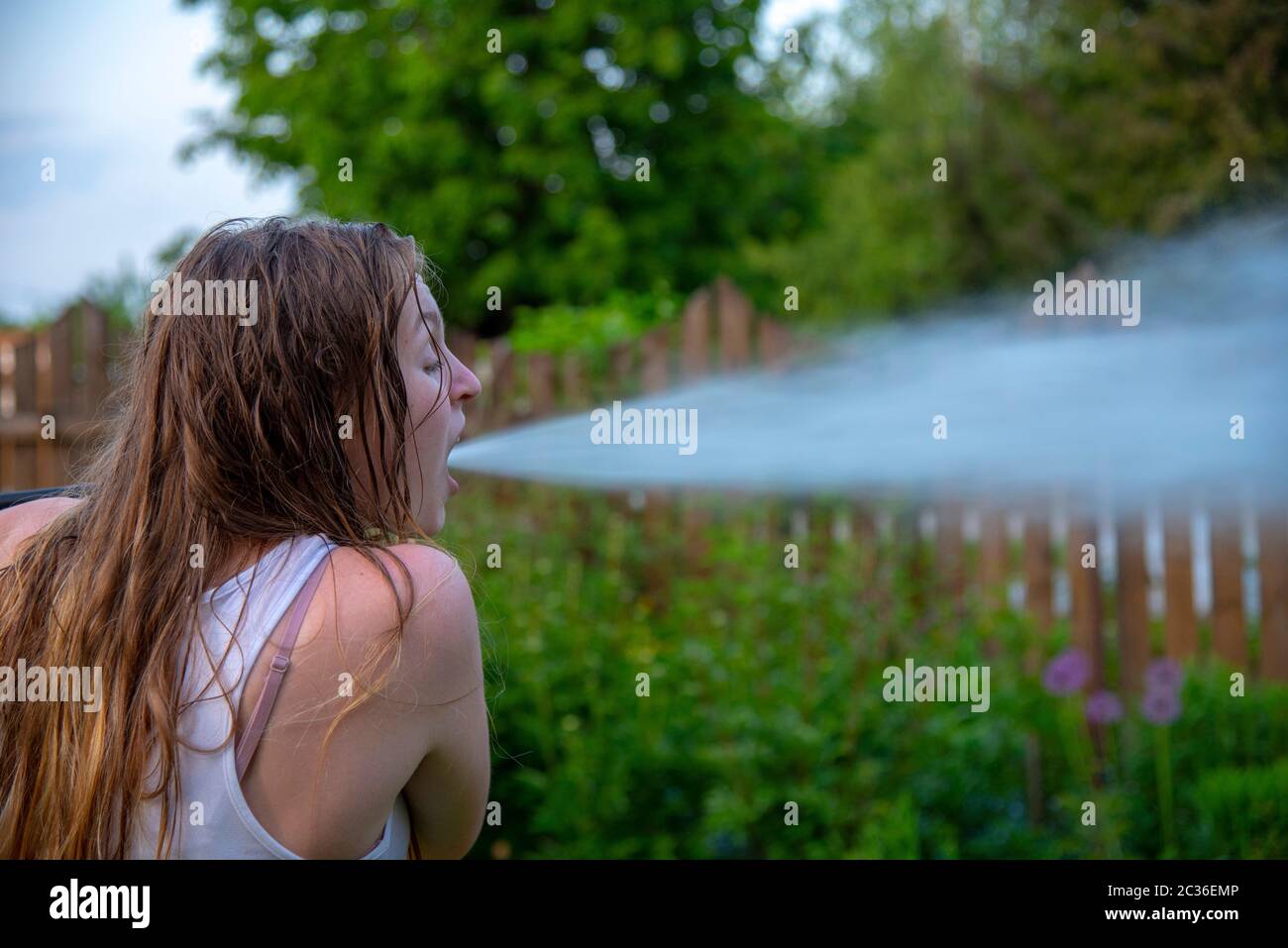A girl with an open mouth. From the mouth as if a powerful jet of water flies out.  Stock Photo