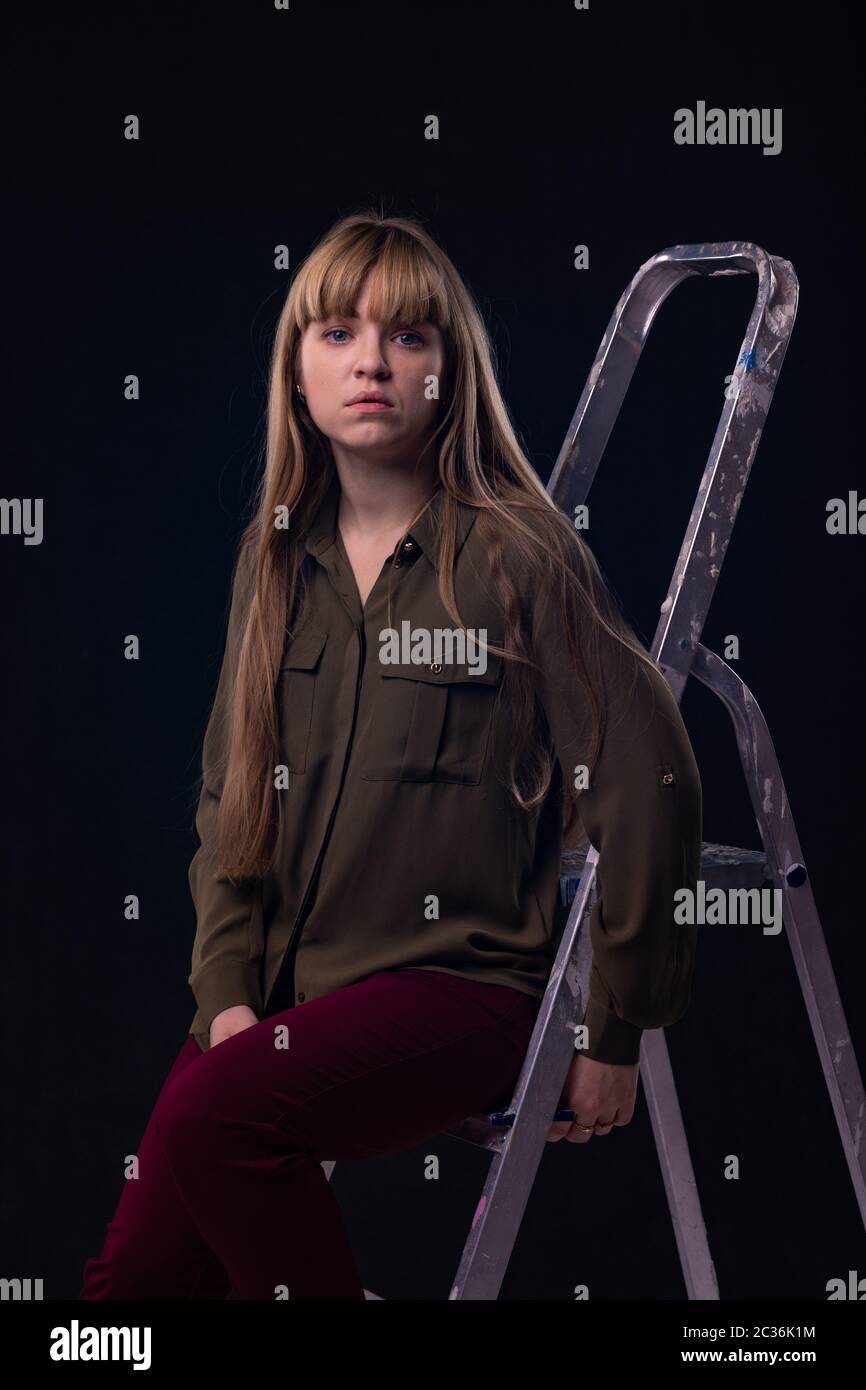 Psychological portrait of a girl sitting on a ladder Stock Photo
