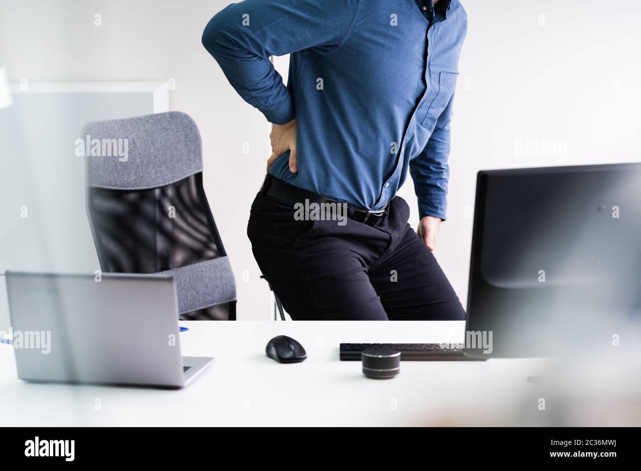 Businessman With Lower Back Ache Standing Near Office Desk Stock Photo
