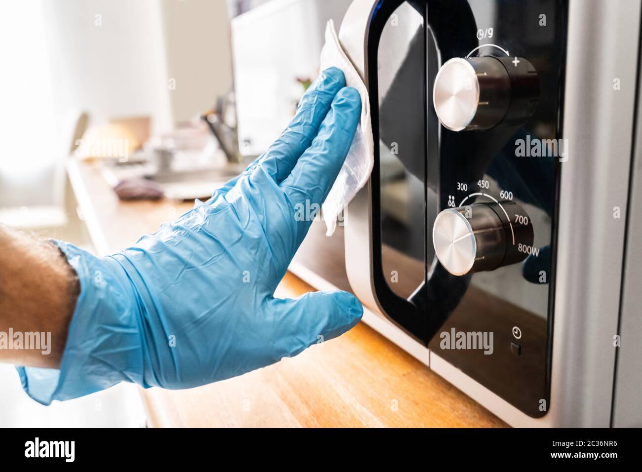 Man Wiping Microwave Oven Handle With Sanitizer Against Virus Infection