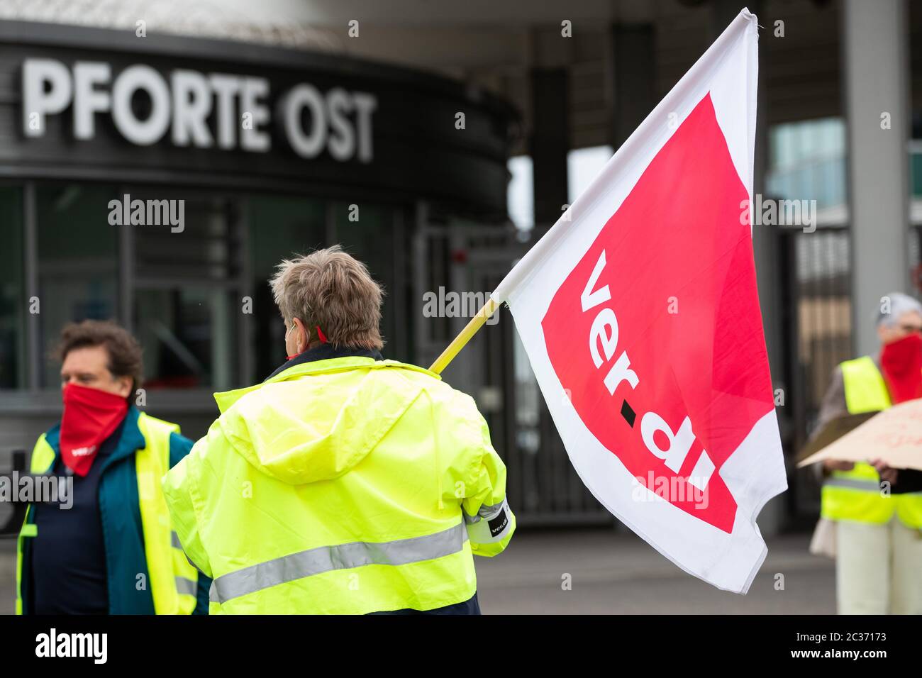 Stuttgart, Germany. 19th June, 2020. A demonstrator stands with a Ver.di flag in front of the East Gate at Stuttgart Airport. The services union Verdi is calling for protest events at many German airports and airline locations. Among other things, it is about the conclusion of a collective agreement between Verdi and the employers' association of ground handling service providers ABL to increase short-time work due to the Corona pandemic. Credit: Tom Weller/dpa/Alamy Live News Stock Photo