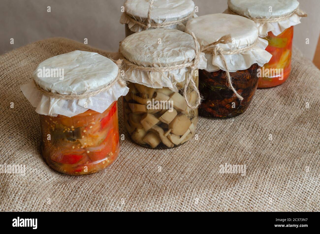 Homemade canned food. Canned food in glass jars. Various canned food on burlap. Preservation and storage of crops. Close-up. Stock Photo