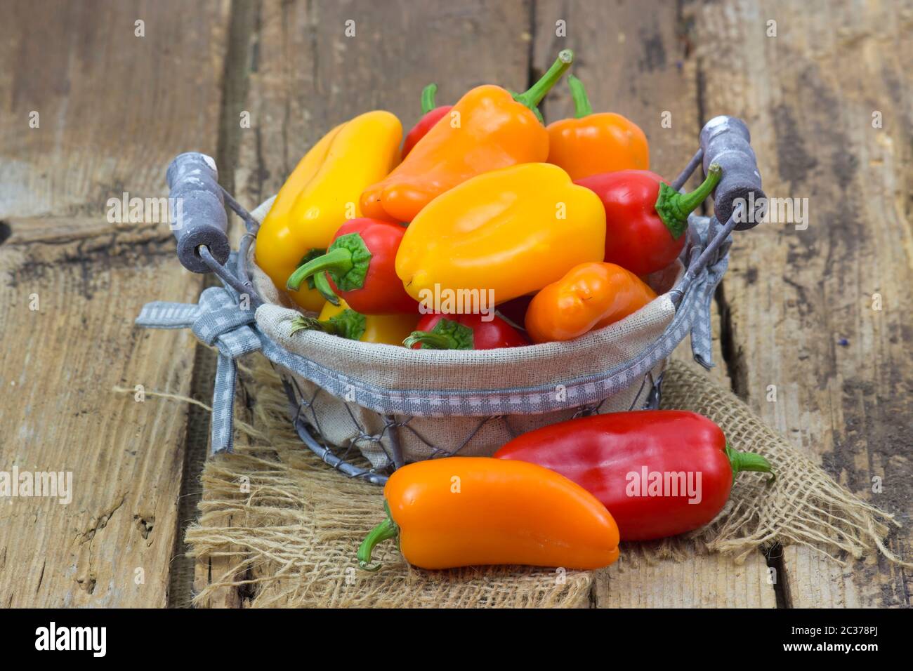 colorful peppers in a basket on wooden background Stock Photo - Alamy