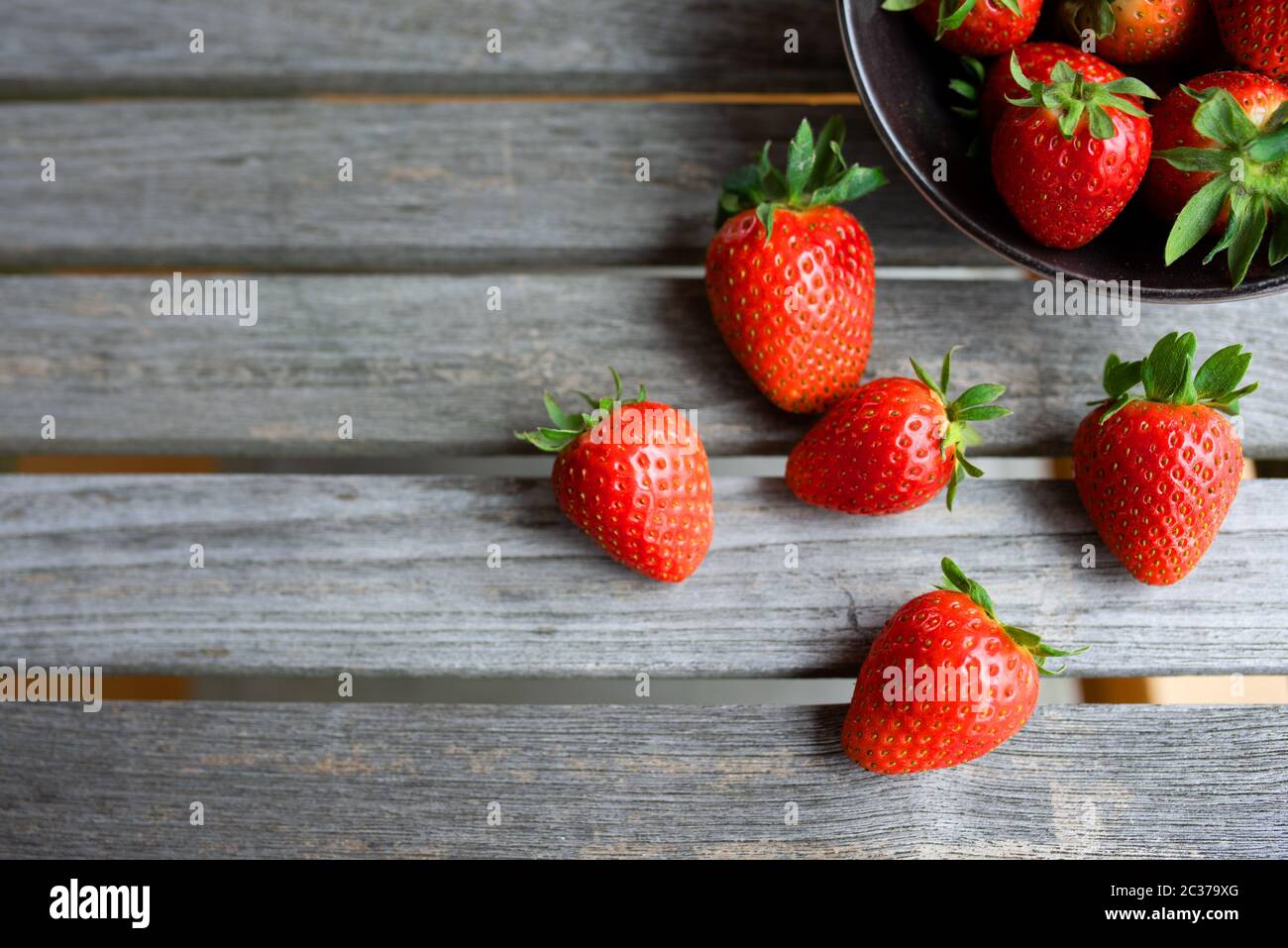 Fresh juicy strawberries on gray wooden planks. Background for a healthy nutrion and lifestyle. Stock Photo