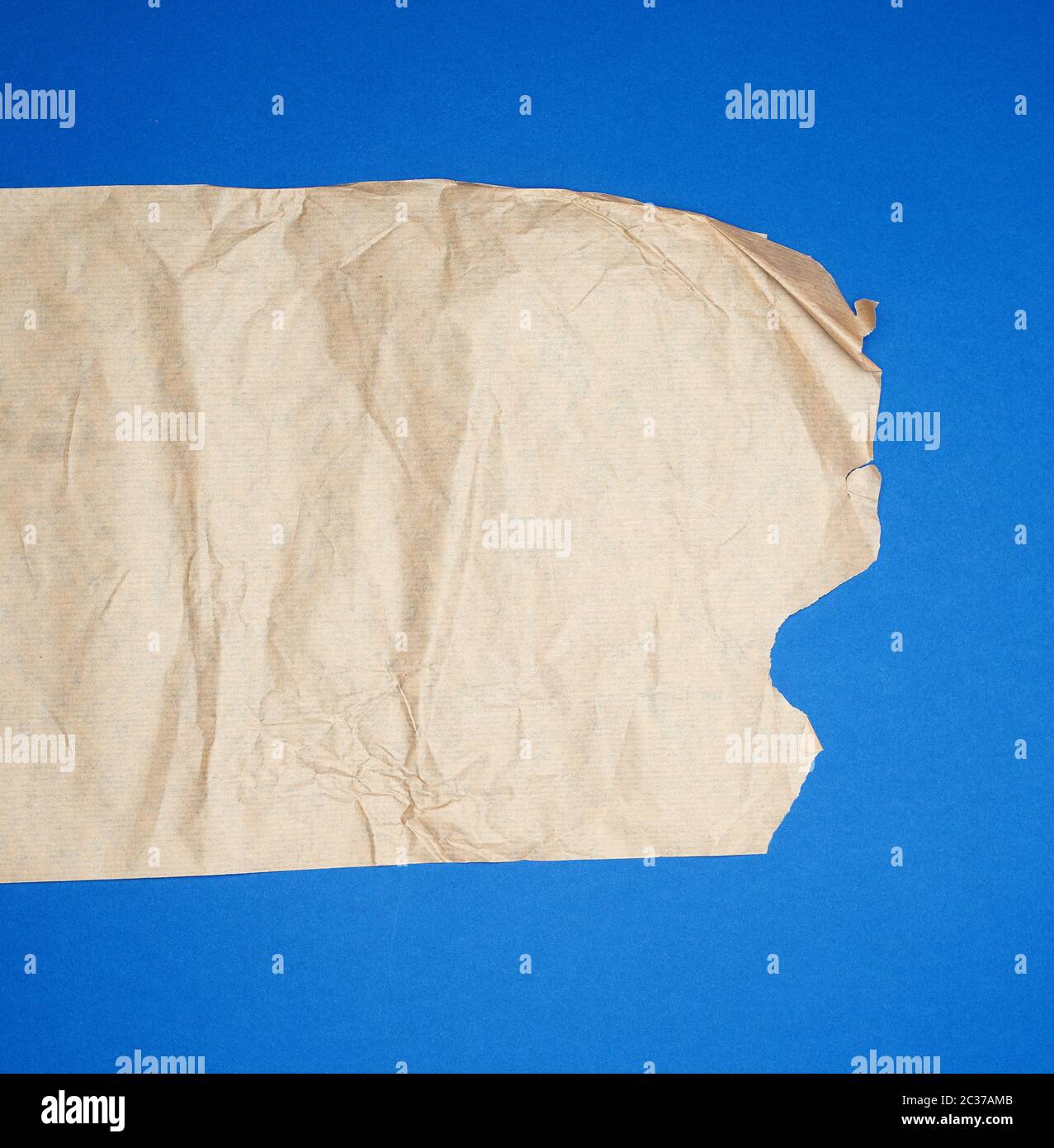 torn brown sheet of paper on a blue background, full frame, close up Stock Photo