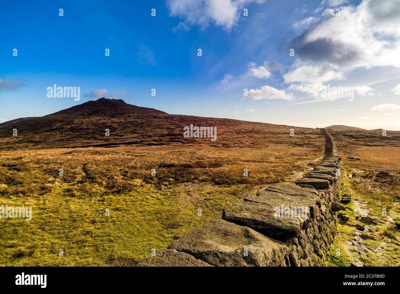 Mourn Wall on the bank of Slieve Donard mountain with blue sky, white clouds and sunlight Stock Photo