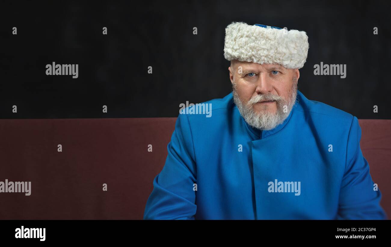 elderly man with a gray beard in a hat and a blue caftan. Cossack costume Stock Photo
