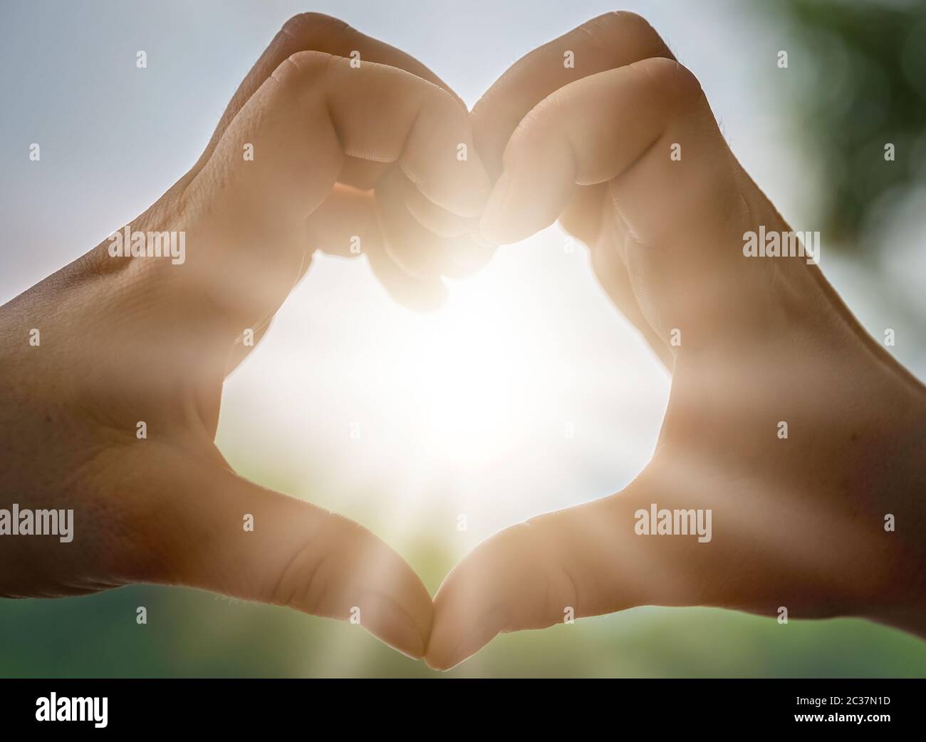 Womans hands catching sunlight sunrays while making heart shape Stock Photo