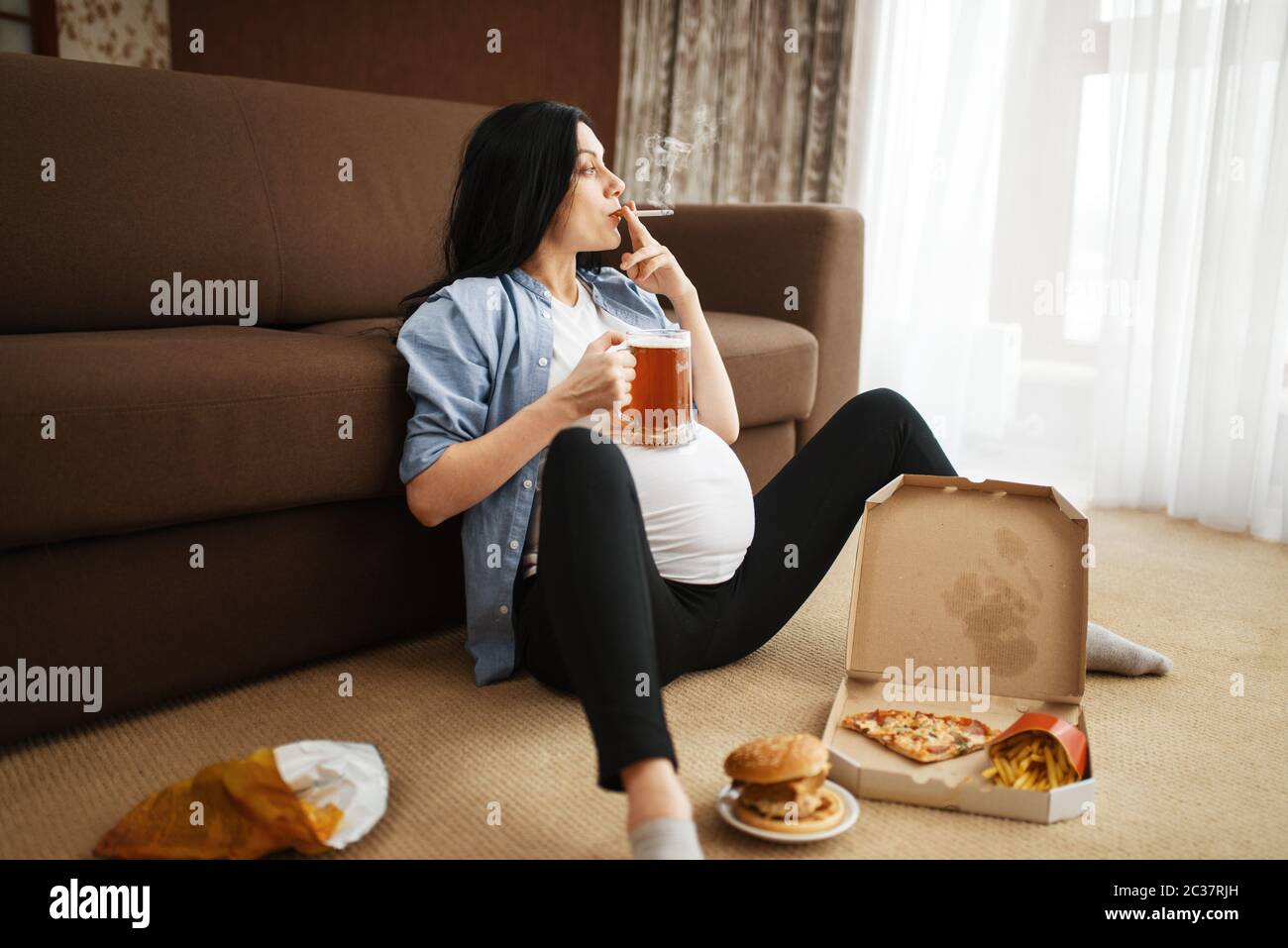 Pregnant woman with belly smoking and drinks beer at home. Pregnancy
