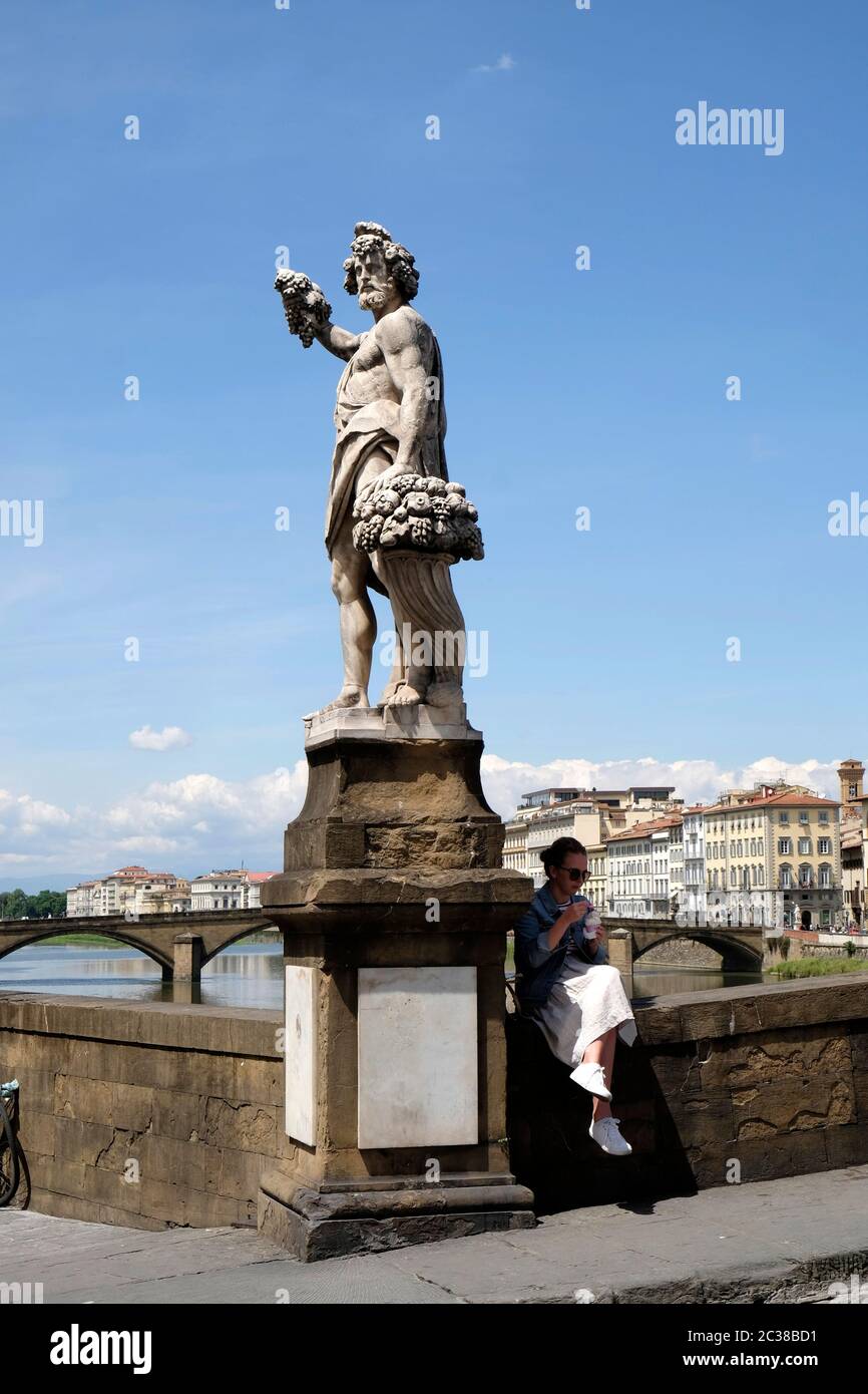 Young woman enjoys an ice cream in the shadow of Bacchus, Ponte Santa Trinita, Florence, Italy. Stock Photo