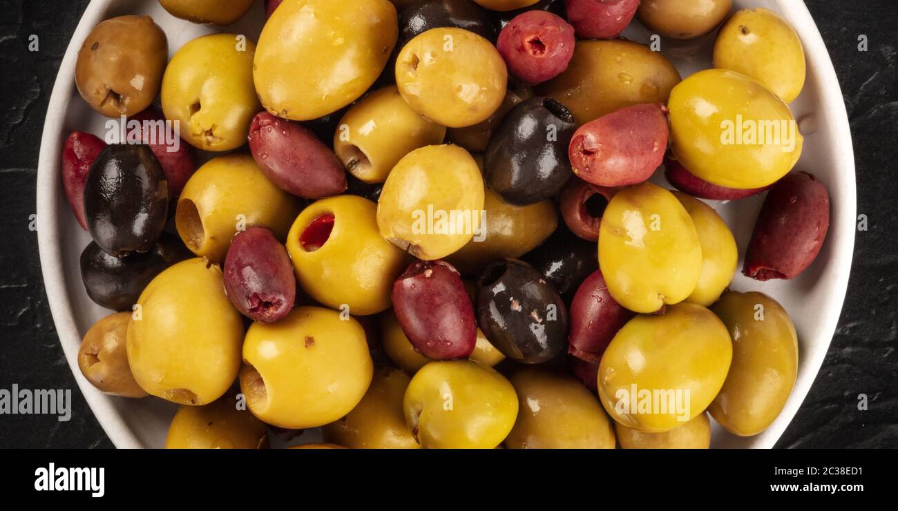 Olives variety close-up panorama. Black, green and red olives, an assortment, shot from above Stock Photo