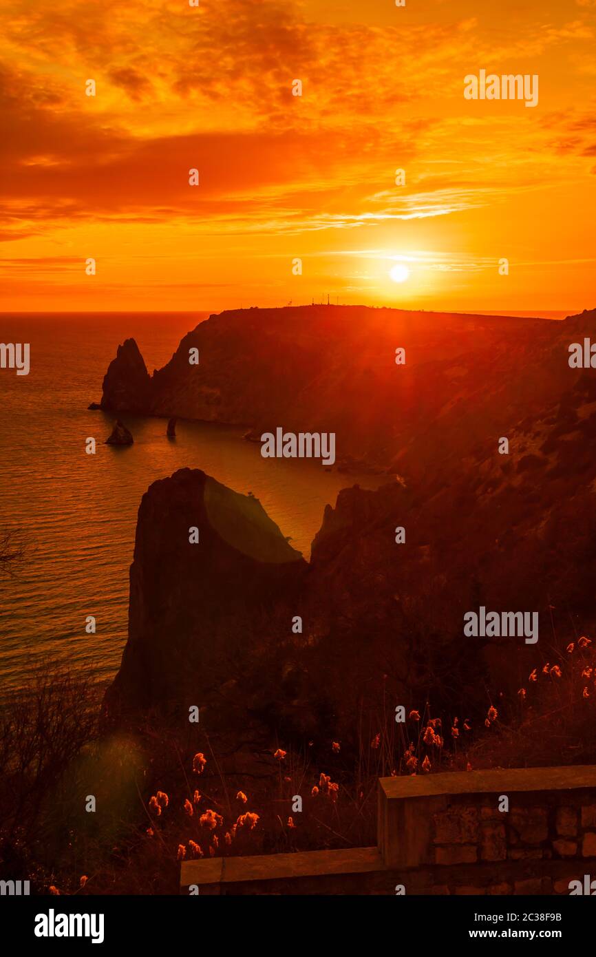 A red burning sunset with the silhouett of cape Fiolent and cliff over ...
