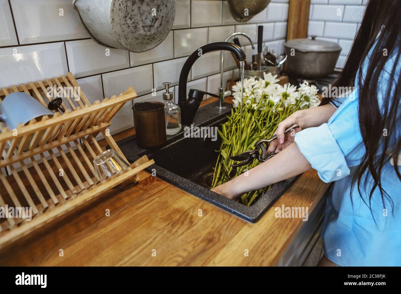 Crop woman cutting flowers in sink Stock Photo