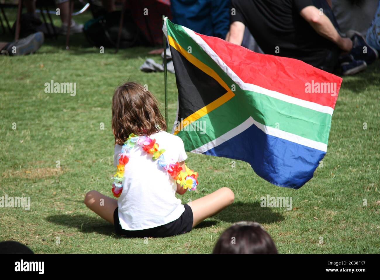 People sit on the grass at UNSW Library Lawn in Kensington, Sydney for the celebration of Nelson Mandela. Stock Photo