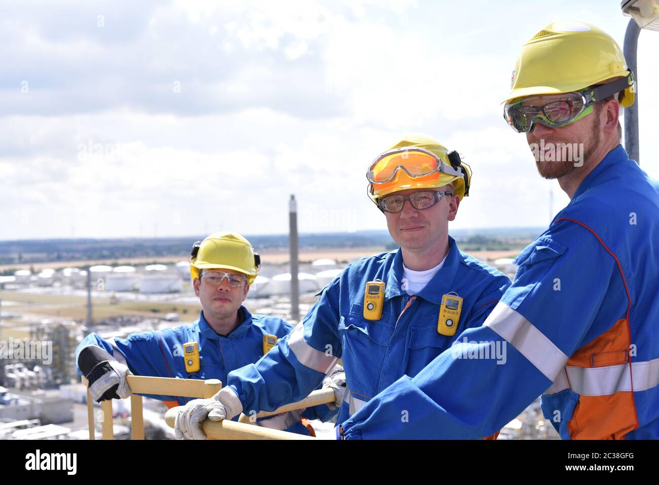 teamwork: group of industrial workers in a refinery - oil processing equipment and machinery Stock Photo
