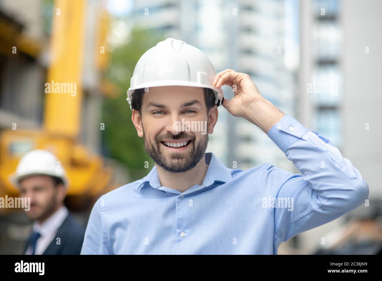 Building site. Foreman holding his helmet with one hand smiling